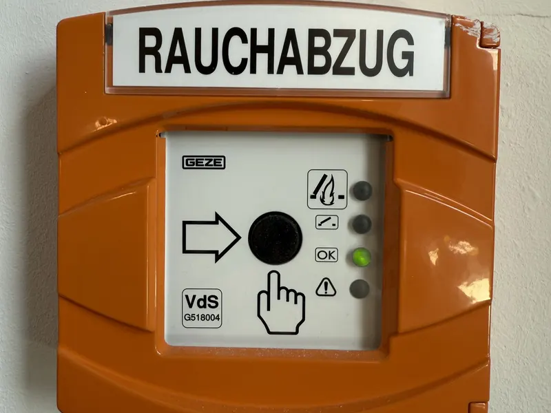 Orangefarbener Rauchabzug-Taster (RWA-Bedienstelle) an der Wand